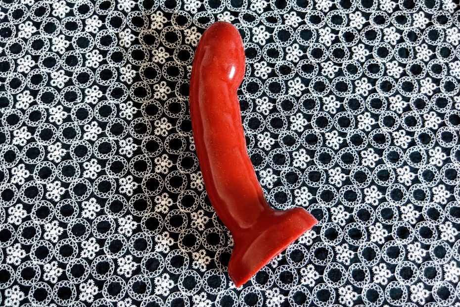 The Tantus Acute laying on its side. It's turned at a slight angle, and is pictured against a black & white background.